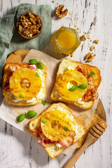 Healthy breakfast or snack, snacks. Toast with caramelized pineapple, bacon, nuts, and ricotta on the kitchen table. Top view flat lay background.