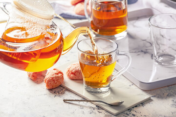 Pouring of hot tea in cup on table