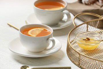 Cups of hot tea with lemon and honey on table