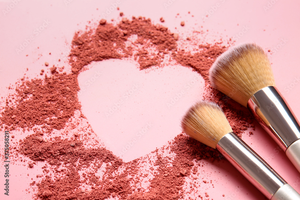 Wall mural Makeup brushes and heart made of cosmetics on color background