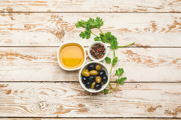Bowls with olives and oil on wooden background