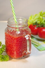 Fototapeta na wymiar Freshly prepared tomato juice with celery leaves in a glass Cup is on the table. The concept of healthy food. It is an element of vegetarianism, keto diet, paleo diet