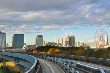 Riding on monorail train to Odaiba Island among modern and Futuristic architecture of Tokyo city and autumn color trees