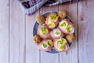 small canapes and biscuits on a plate on a wooden table, top view  