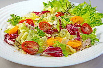 Salad of cabbage, tomatoes, lettuce, seasoned with vegetable oil on a white plate. The concept of healthy eating. Dish for vegan, Keto diet and paleo diet.