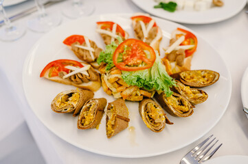 Pancakes with caviar in a white plate on the table. A delicious stylish dish. Serves dinner on a festive table. Food on festive table at wedding banquet.