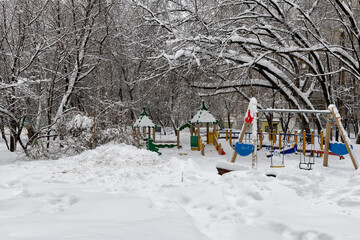 Snow-covered playground in town after snowfall in winter. 