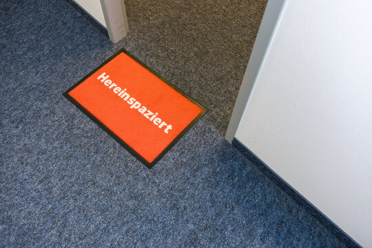 Fußmatte vor einer Bürotür mit Aufschrift Hereinspaziert