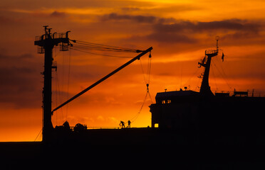 夕日を浴びる貨物船の荷役作業、那覇港