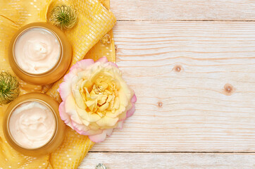 round jars of cosmetic cream. Cosmetic mock up bottles. Flat lay top view copy space. Natural skincare beauty product concept. on a wooden background and an yellow napkin