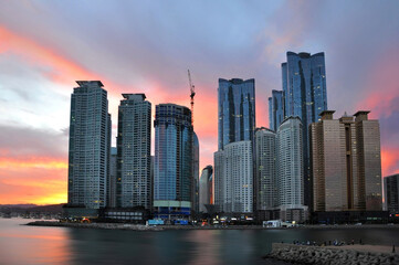Urban landscape of modern Busan city skyline with skyscrapers, view over colorful sunset at Haeundae beach, Busan, South Korea