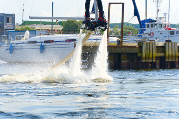 man having fun on Flyboard. Flyboarding in a sunny summer day at river in harbor. Extrime water activity flyboard.