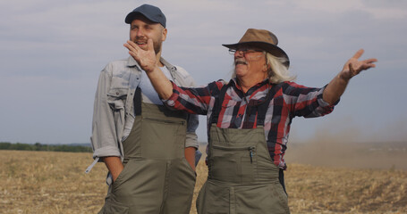 Naklejka premium Positive farmers dispersing soil in air