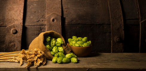 Beer. Still life with Vintage beer barrel and glass light beer. Fresh amber beer concept. Green hop and gold barley on wooden table. Ingredients for brewery. Brewing traditions