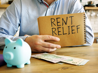 Rent relief. A man at home holds a handwritten lettering.