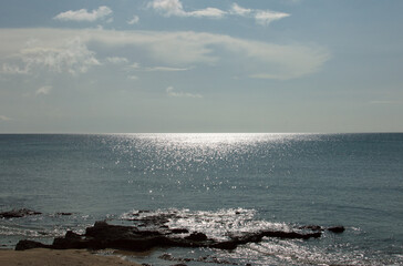 Fototapeta na wymiar 岩の海岸と鮮明な水平線の海に太陽の光が反射している