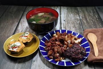 Traditional breakfast menu set in Thailand, steamed sticky rice serving with deep fried pork meat, fish curry cake, fried egg and pork blood soup. 