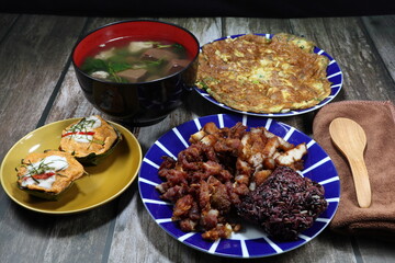 Traditional breakfast menu set in Thailand, steamed sticky rice serving with deep fried pork meat, fish curry cake, fried egg and pork blood soup. 