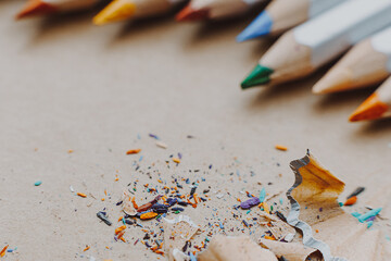 background for art workshop or school class on drawing and fine arts: sharpened colored pencils and shavings on a drawing sheet