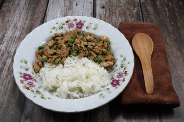 Traditional fried and stirred minced or marinated pork with cutting green bean serving with cooked jasmine rice on the plate. Famous Thai spicy food in Asia restaurant. 