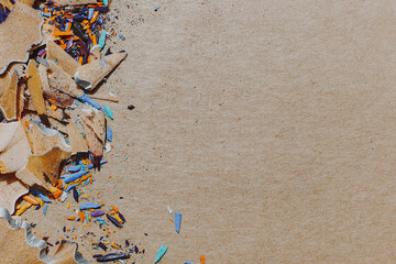 background for art workshop: shavings from sharpening colored pencils lying on a craft paper background with space for your text or advertising