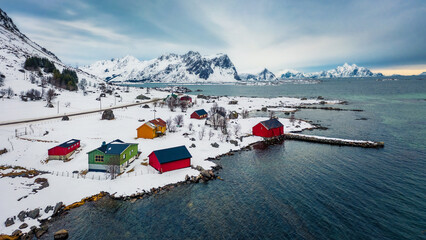 View from flying drone of Justad fishing village on Vestvagoy island. Colorful wooden houses on Lofoten Islands, traditional Norwegian architecture. Gloomy winter seascape of Norwegian sea.