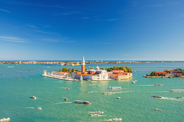 Aerial panoramic view of San Giorgio Maggiore island with Campanile San Giorgio in Venetian Lagoon, sailing boats in Giudecca Canal, Lido island, blue sky background, Venice city, Veneto Region, Italy