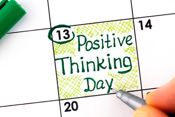 Woman fingers with pen writing reminder Positive Thinking Day in calendar.