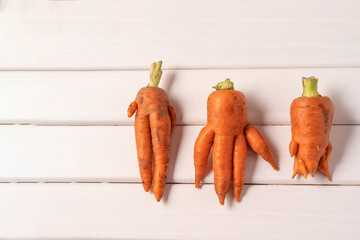 Ugly curved carrots on white wooden background