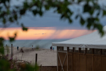 Piękny zachód słońca nad morzem. Na horyzoncie widać jak pada deszcz. Człowiek patrzy na zachód słońca. © Anastasiia