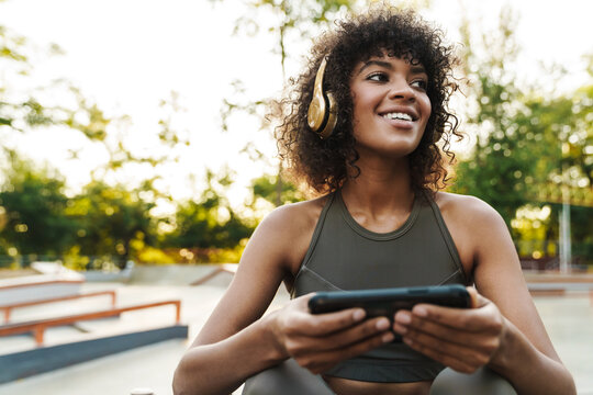 Image of african american sportswoman using cellphone and headphones - Powered by Adobe