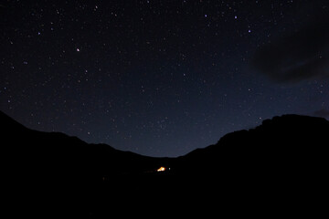 Starry sky in the mountains. Tourist tent in the mountains under the starry sky.