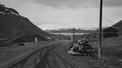Snow scooters waiting for the winter next to a road in Longyearbyen on Svalbard. Snow covered mountain in the background