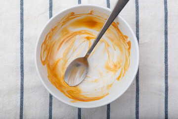 Dirty dish, plate with spoon and sauce, top view