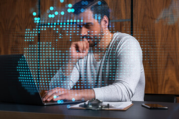 A serious caucasian manager in casual wears, using laptop to develop a new worldwide supply chain. Double exposure. globe and map hologram.