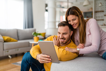 Couple in love using tablet computer at home and having fun