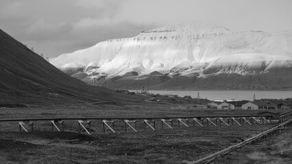 Pipeline overground construction in the town Longyearbyen on the island Spitsbergen. Snow covered mountain in the background.