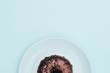Chocolate donut on a blue plate and a blue background.