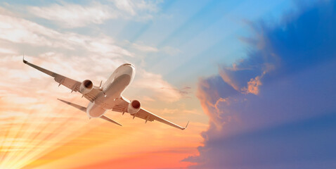 Fototapeta na wymiar White passenger airplane in the clouds at sunset - Travel by air transport