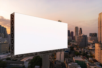 Blank white road billboard with Bangkok cityscape background at sunset. Street advertising poster, mock up, 3D rendering. Side view. The concept of marketing communication to promote or sell idea.