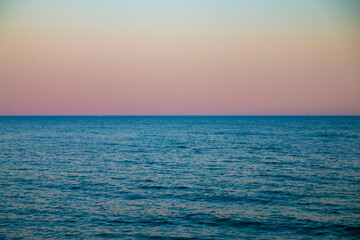 A scenic view with blue sea and colorful sky after sunset in Spain