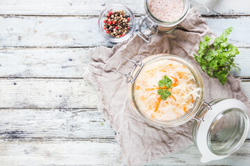 Glass jar with homemade sauerkraut on rustic wooden table, top view