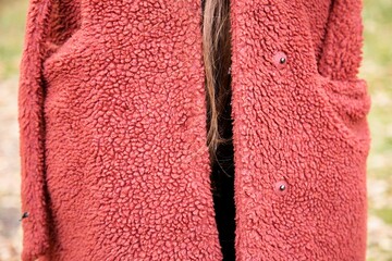 Young woman wearing large red fleece as a winter coat, with brown hair strand hanging