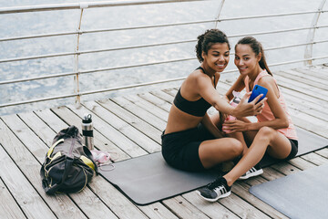 Image of happy multinational sportswomen taking selfie on cellphone