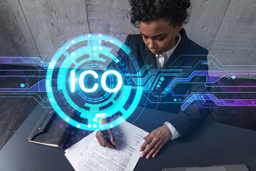 A woman signs contract and ico symbol hologram. Concept of initial coin offering. Multiexposure....