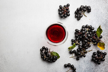 Fototapeta na wymiar homemade black chokeberry wine or liqueur with ripe berries, top view