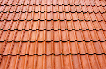 Obraz na płótnie Canvas Old roof tiles on the roof of an house as seamless pattern. Red tiles roof texture architecture background, detail of house close up.