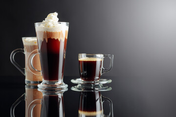 Espresso, Irish coffee, and latte on a black reflective background.