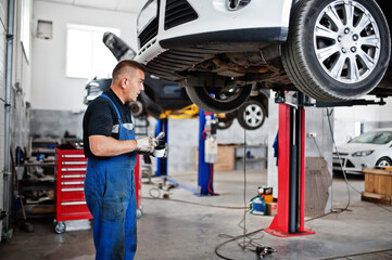 Car repair and maintenance theme. Mechanic in uniform working in auto service.
