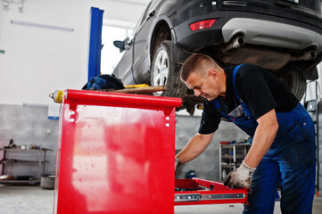 Car repair and maintenance theme. Mechanic in uniform working in auto service.